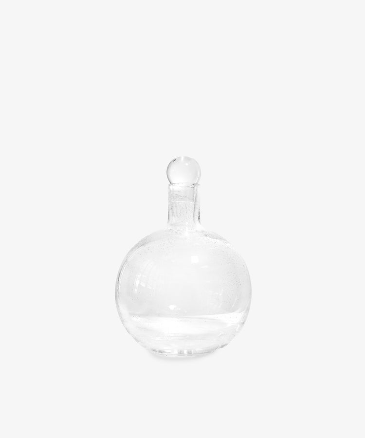 The Bubble Glass Carafe features a clear, round design with a narrow neck and matching glass stopper, displayed against a plain white background.