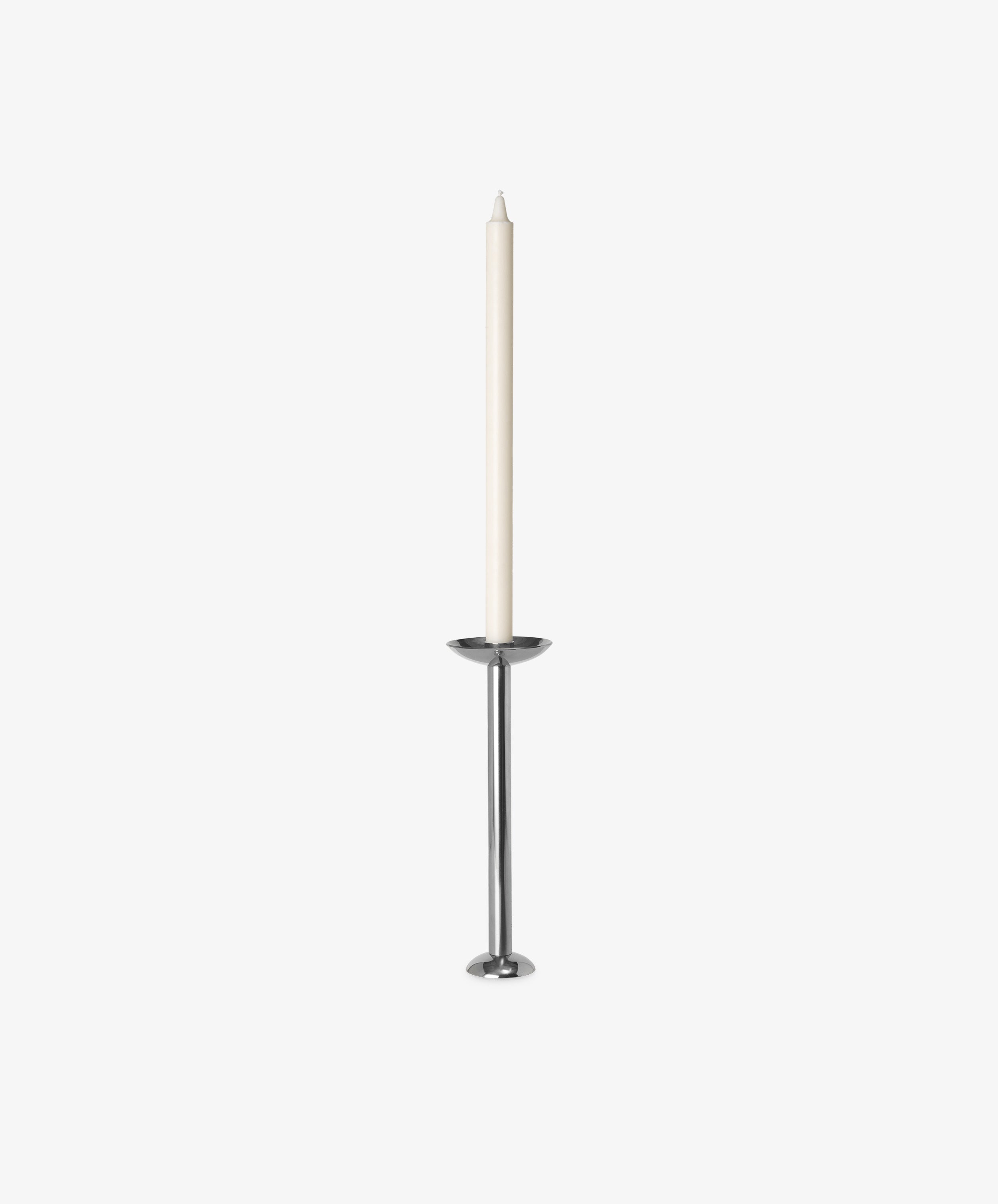 A tall white taper candle stands in the Metal Champagne Candle Holder, a modern, minimalist piece with a polished stainless steel finish, set against a plain white background.