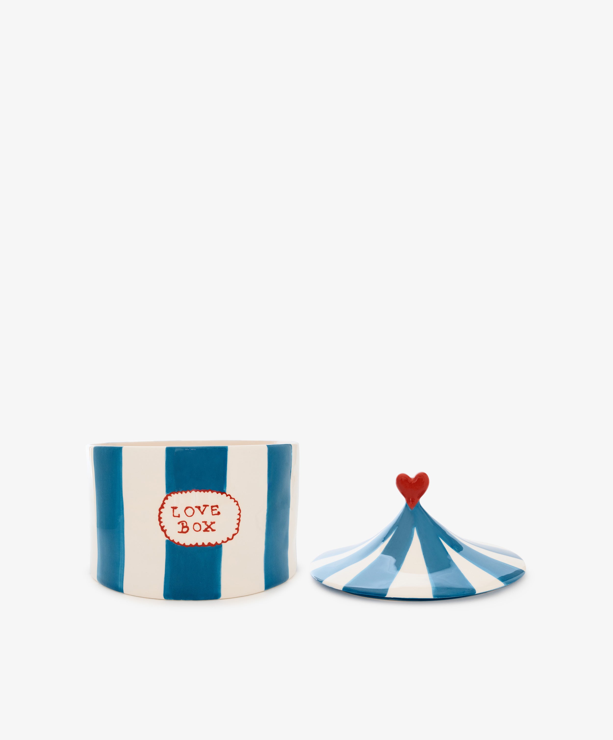 The Love Box is a blue and white striped ceramic container with a matching lid topped by a small red heart, designed to resemble a circus tent. Placed on a plain white background, this hand-crafted decorative keepsake box adds charm to any space.