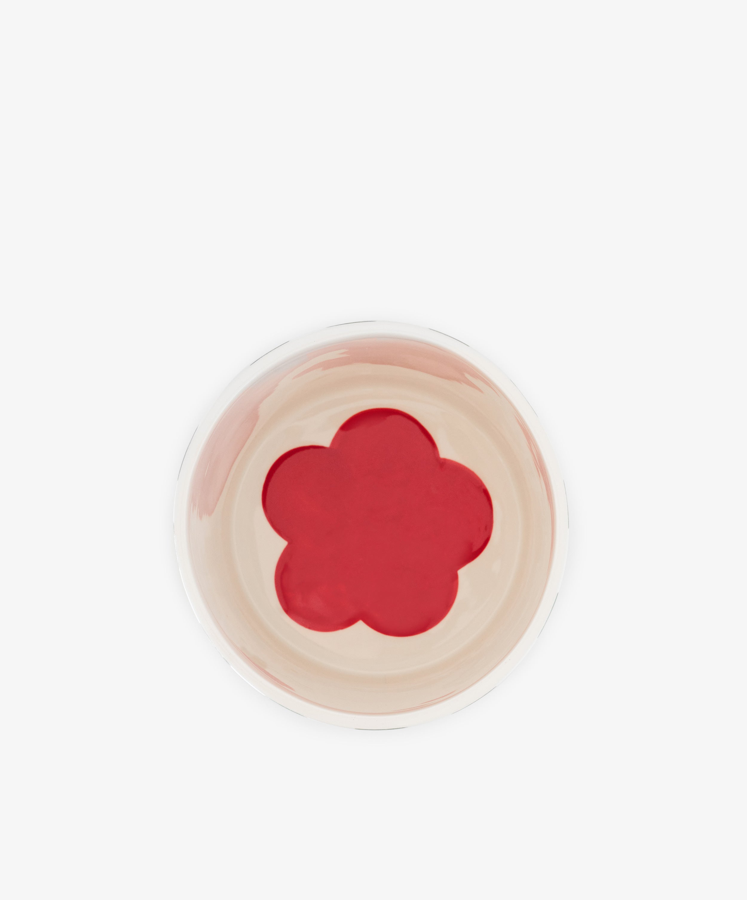 A top-down view of the Magic Box, a hand-crafted Portugal ceramic bowl featuring a beige interior and a red, five-petal flower shape centered on the bottom.