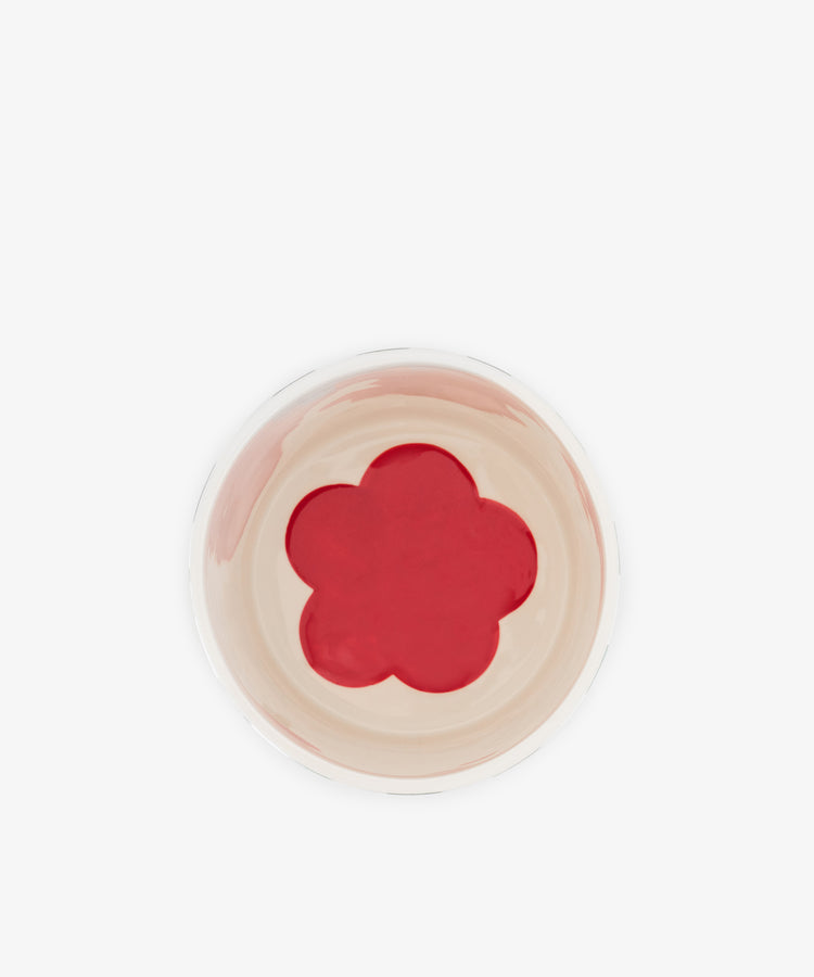 A top-down view of the Magic Box, a hand-crafted Portugal ceramic bowl featuring a beige interior and a red, five-petal flower shape centered on the bottom.