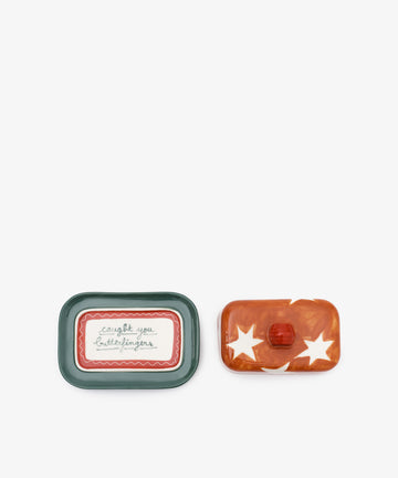 Two rectangular Butterfingers Butter Dishes: one green-rimmed with a text label, the other orange with white stars and a knob. Each handmade piece reflects Laetitia Rouget’s playful style for your table.