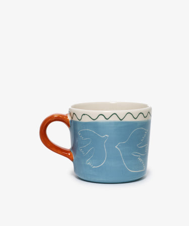 Colombe Mug by Laetitia Rouget. Light blue painted stoneware mug with dove illustrations and orange handle.