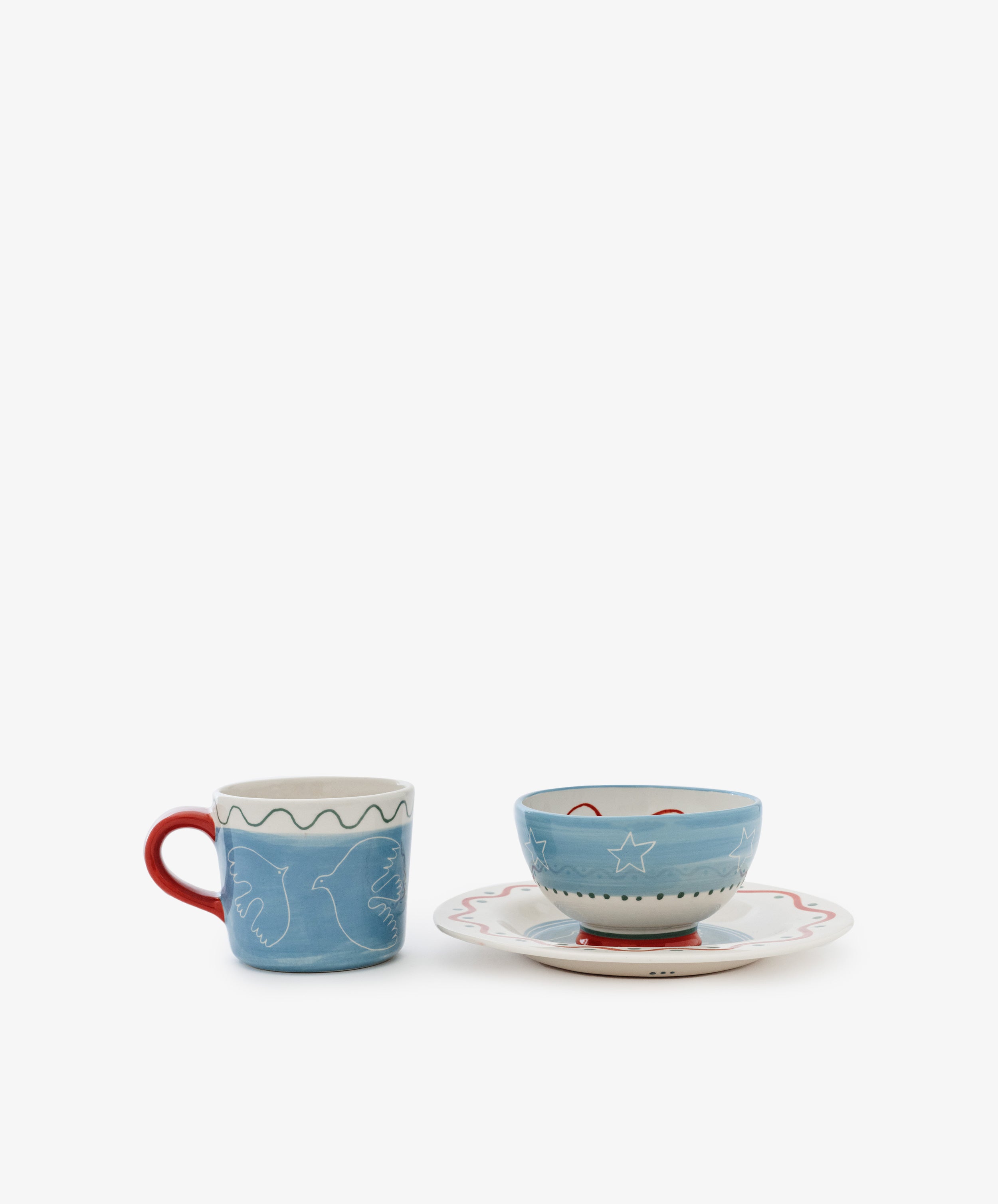 The Colombe Bundle features a blue mug with a red handle and white line art beside a blue bowl adorned with white stars on a matching saucer with a wavy red rim, all set against a white background.