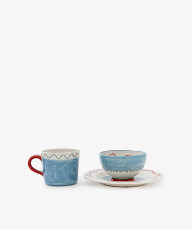 The Colombe Bundle features a blue mug with a red handle and white line art beside a blue bowl adorned with white stars on a matching saucer with a wavy red rim, all set against a white background.
