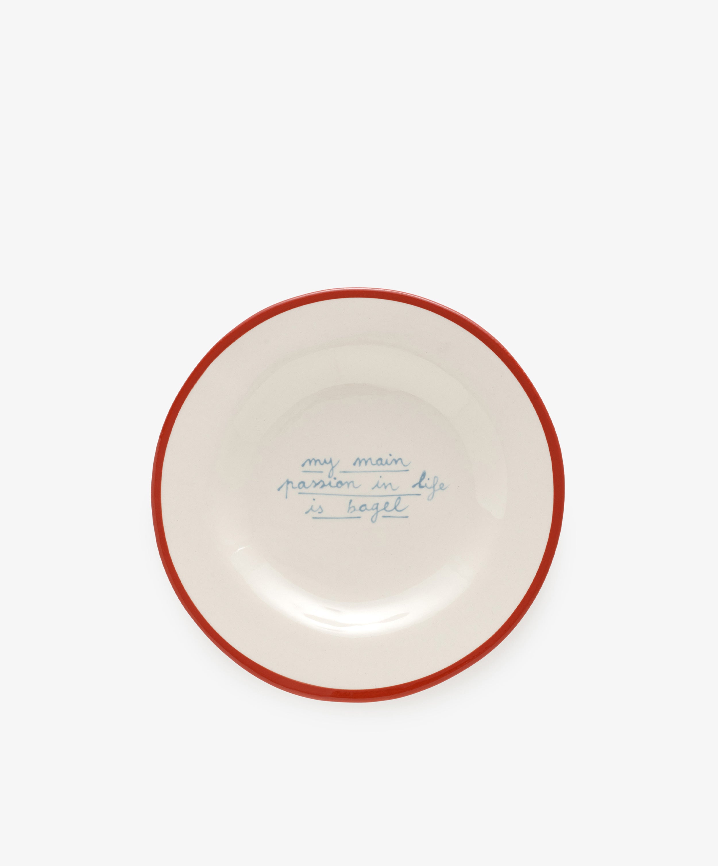 The My main passion in life is bagel plate by Laetitia Rouget is handmade, white with a red rim, and features blue handwritten text in the center.