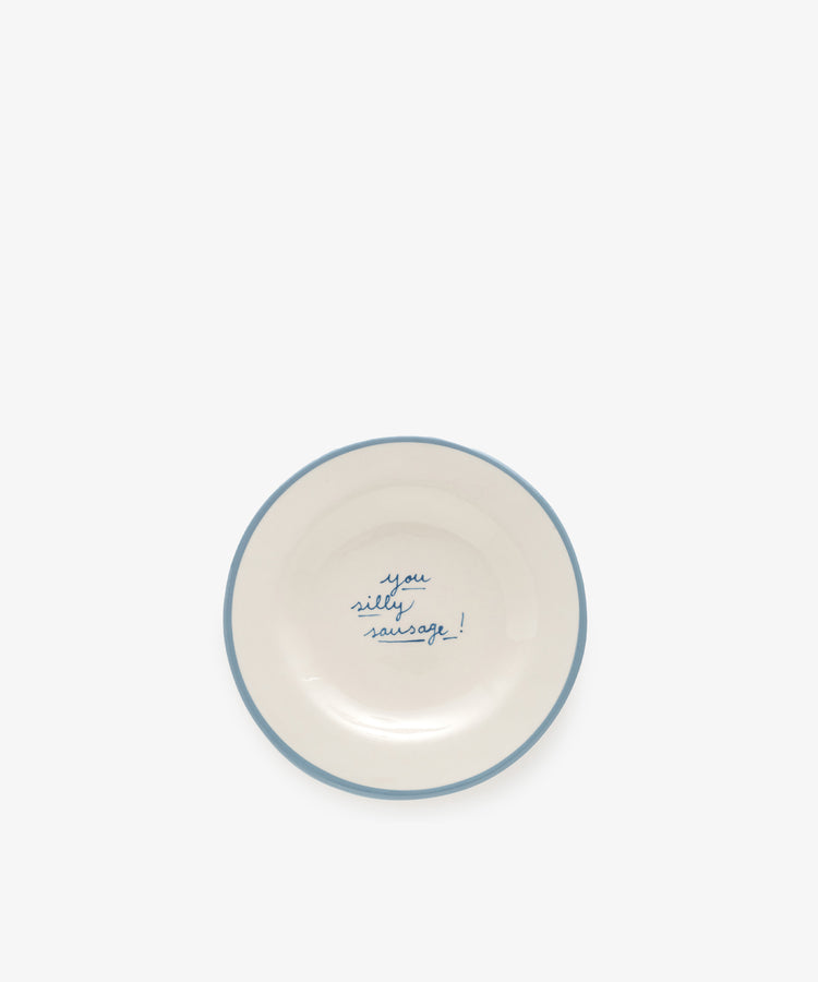 The “You silly sausage!” plate is a white ceramic dish with a light blue rim and the handwritten phrase “you silly sausage!” in blue text at the center.