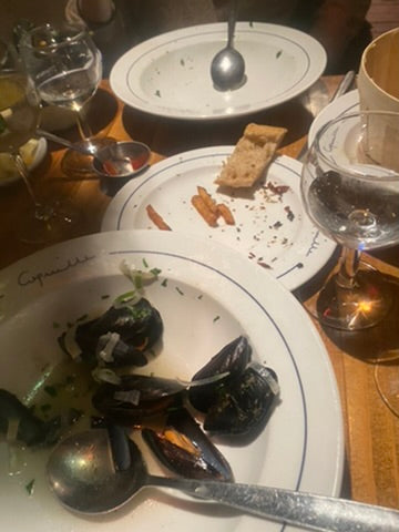 Dinner table with plates of mussel shells, bread, and wine glasses
