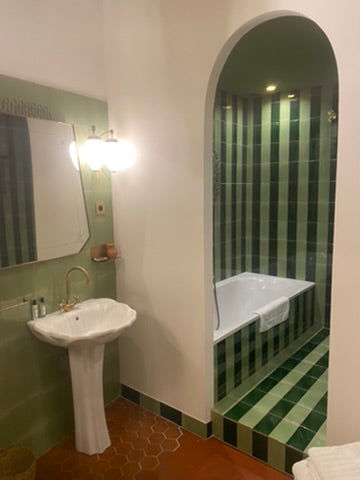 Bathroom with pedestal sink and green-tiled bathtub alcove