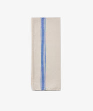 The Métis Tea Towel, crafted from a folded beige linen-cotton blend and adorned with three parallel blue stripes running vertically along one side, is displayed on a plain white background.
