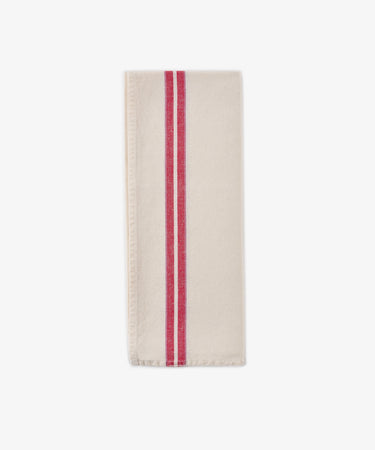 A folded Métis Tea Towel—cream-colored linen with two parallel red stripes running vertically near one edge, evocative of classic French kitchen linens—is displayed on a plain white background.