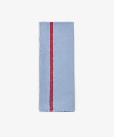 A folded Métis Tea Towel in light blue linen, featuring a single vertical red stripe near the left edge, displayed on a plain white background.