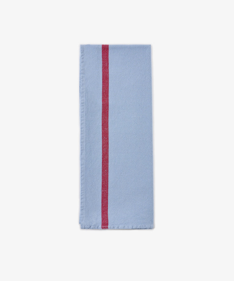 A folded Métis Tea Towel in light blue linen, featuring a single vertical red stripe near the left edge, displayed on a plain white background.