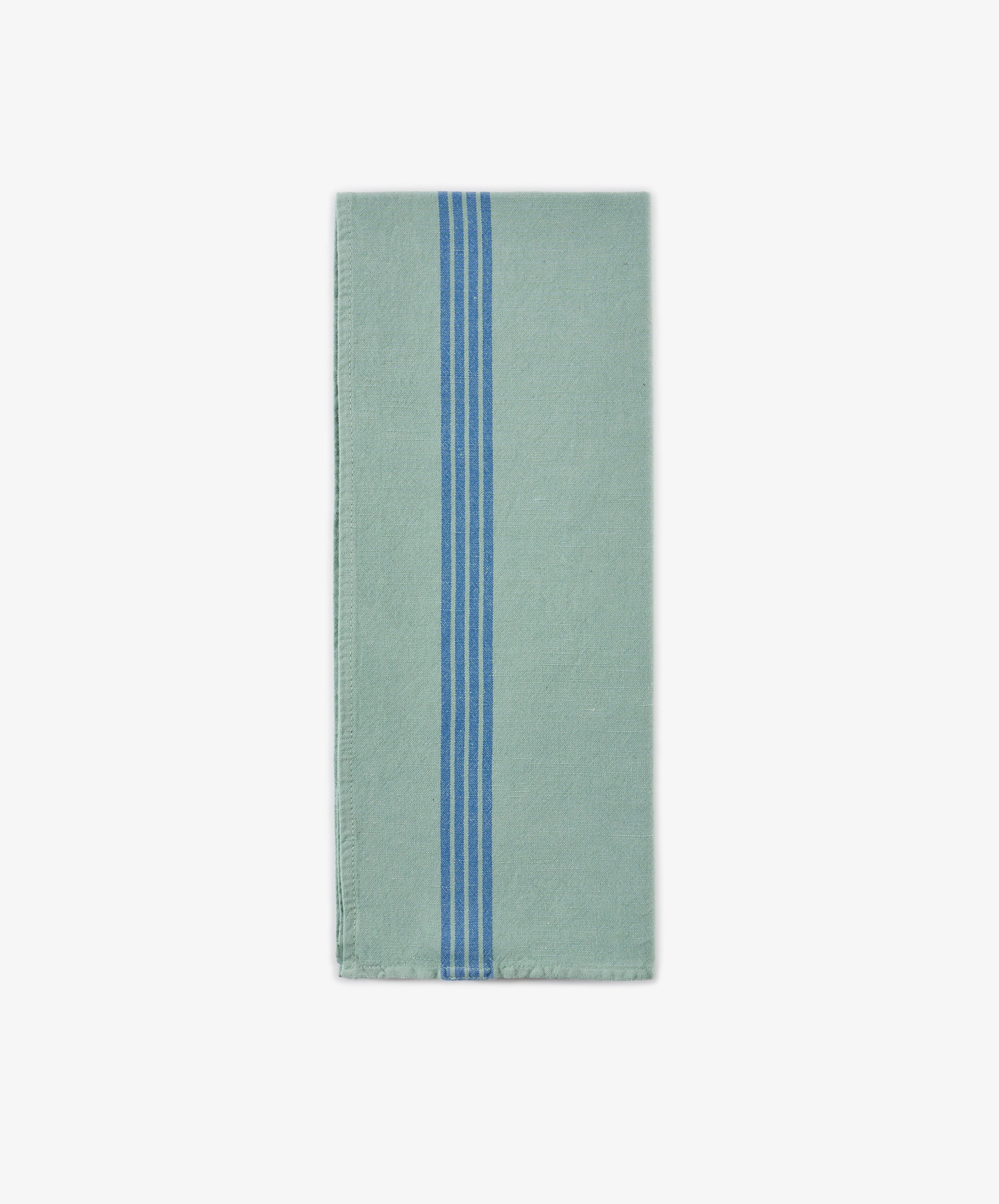 The Métis Tea Towel, a folded light green cloth featuring three vertical blue stripes near the center, is displayed on a plain white background and evokes the look of French kitchen linens and classic vintage striped tea towels.