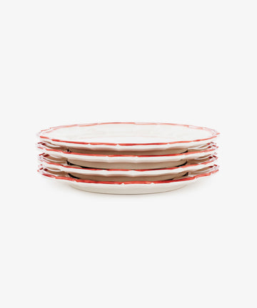 A set of four Eva Melamine Dinner Plates, featuring white surfaces with red, slightly scalloped edges, is arranged on a white background to highlight durable dinnerware that blends classic style with everyday practicality.