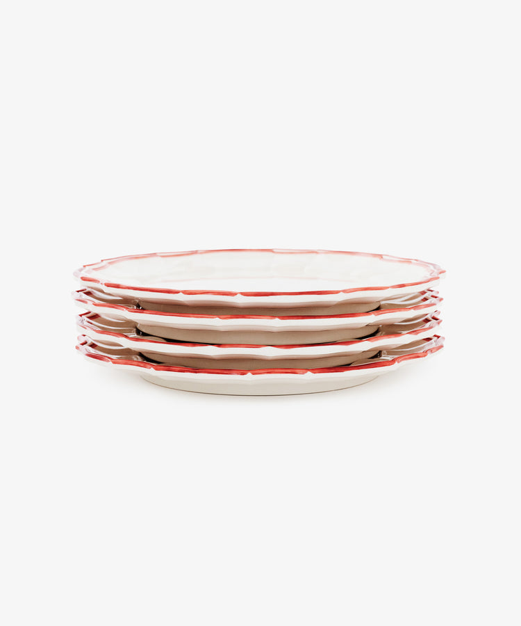 A set of four Eva Melamine Dinner Plates, featuring white surfaces with red, slightly scalloped edges, is arranged on a white background to highlight durable dinnerware that blends classic style with everyday practicality.