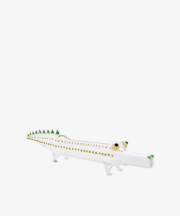 Handcrafted from hand-blown borosilicate glass, the Crokygris Centerpiece features vibrant green spikes along its back, brown spots, and two large eyes—all set against a plain white background. Inspired by the artistry of Massimo Lunardon, this exquisite glass crocodile figurine is a striking and playful addition to any collection.