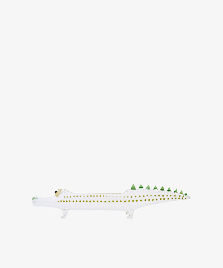 The Crokygris Centerpiece, a white ceramic crocodile figurine adorned with yellow spots and green triangular spikes along its back and inspired by the playful glass crocodile centerpiece designs of Massimo Lunardon, is shown on a plain white background.