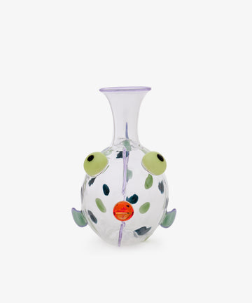 Dotfish Decanter—clear glass vase reminiscent of a round fish, featuring green eyes, an orange mouth, small fins, and whimsical purple accents in the style of Massimo Lunardon’s Murano glass creations, set against a plain white background.