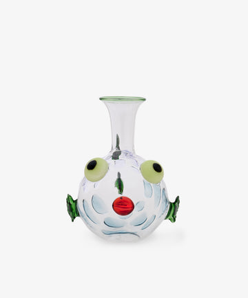 The Molly Decanter is a clear glass vase shaped like a fish, featuring green fins, yellow eyes, and a red mouth. Handcrafted in exquisite Murano glass in the style of Massimo Lunardon, it is shown against a plain white background.