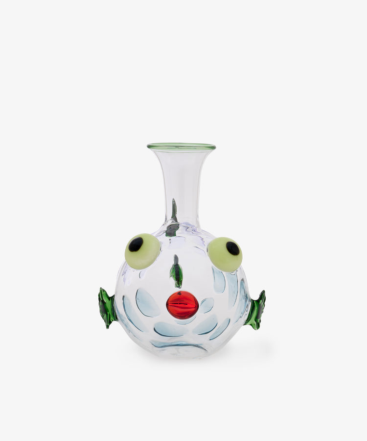 The Molly Decanter is a clear glass vase shaped like a fish, featuring green fins, yellow eyes, and a red mouth. Handcrafted in exquisite Murano glass in the style of Massimo Lunardon, it is shown against a plain white background.