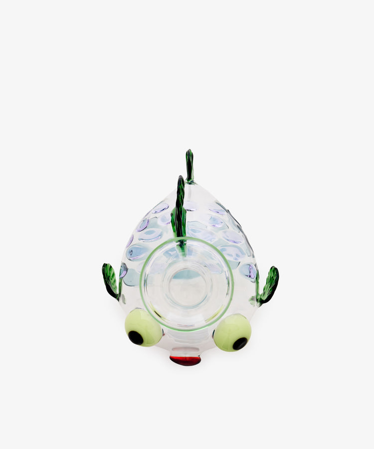 The Molly Decanter is a clear glass bowl shaped like a fish, crafted in the style of Murano glass, featuring green fins, large round yellow eyes, and a red mouth, photographed on a plain white background.