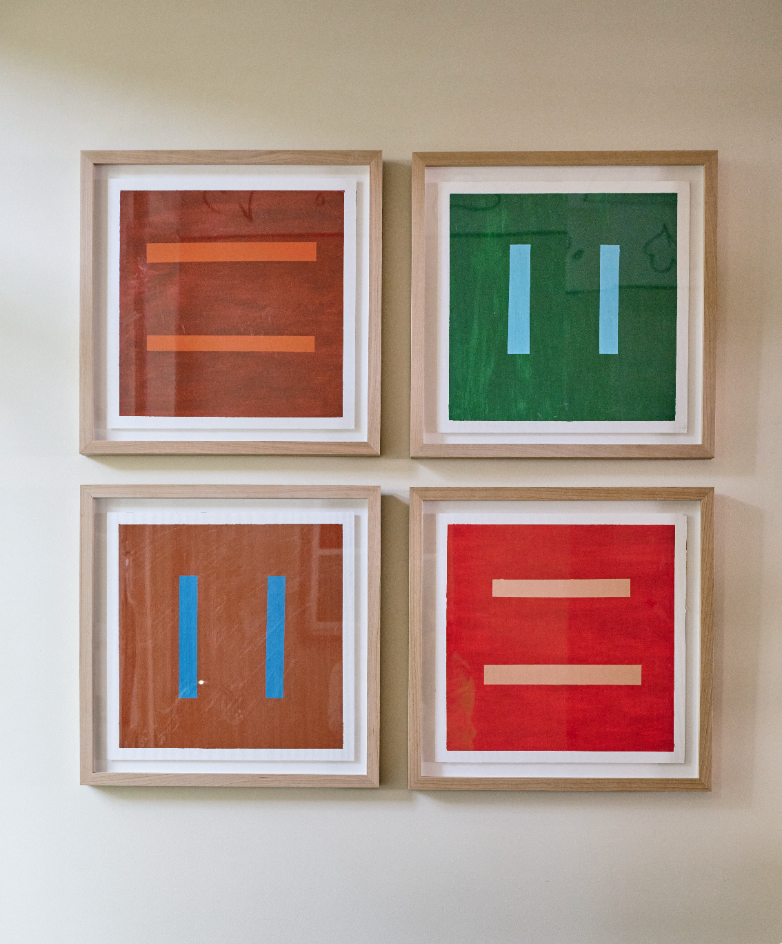 Grid of four square framed Color Field paintings hung on wall.