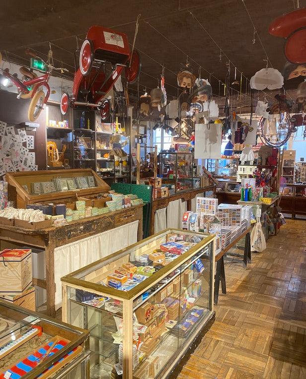 Vintage shop interior with glass display cases, hanging toys, and shelves of assorted goods