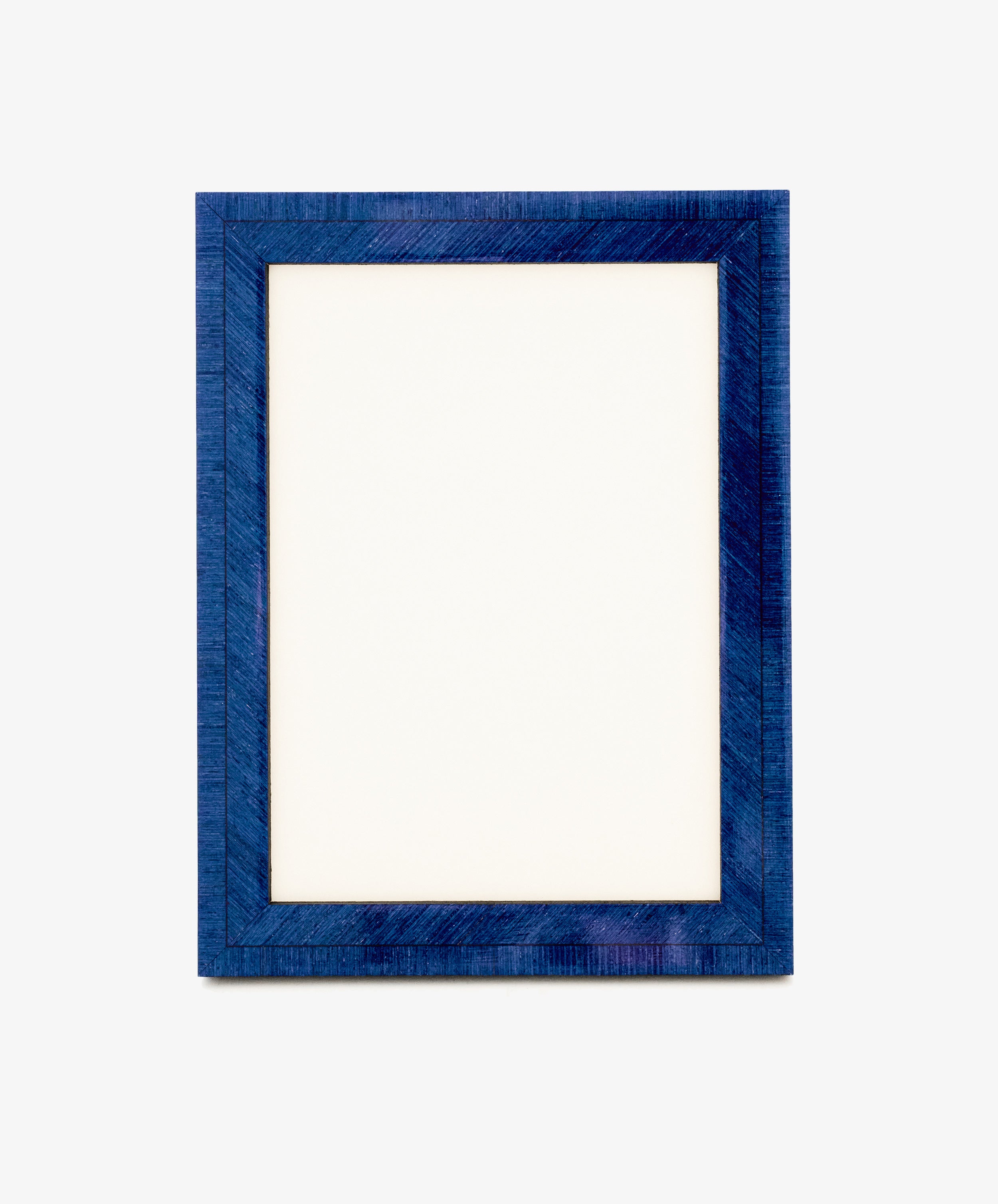 A blank white sheet of paper inside the rectangular, textured Torino Frame finished in deep blue, set against a plain light background, evokes the elegance of geometric marquetry in its subtle patterns.
