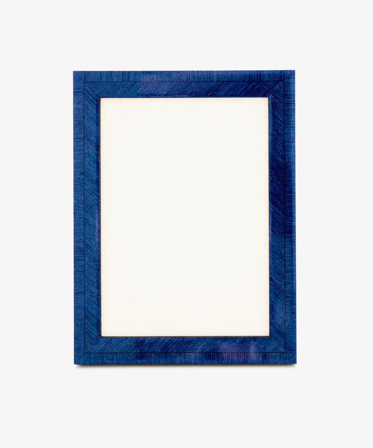 A blank white sheet of paper inside the rectangular, textured Torino Frame finished in deep blue, set against a plain light background, evokes the elegance of geometric marquetry in its subtle patterns.