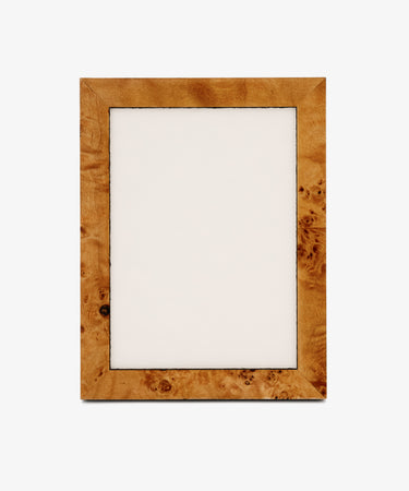 The Torino Frame, a rectangular wooden design with a light brown finish and subtle geometric marquetry details, features an empty white center and stands upright against a plain background.
