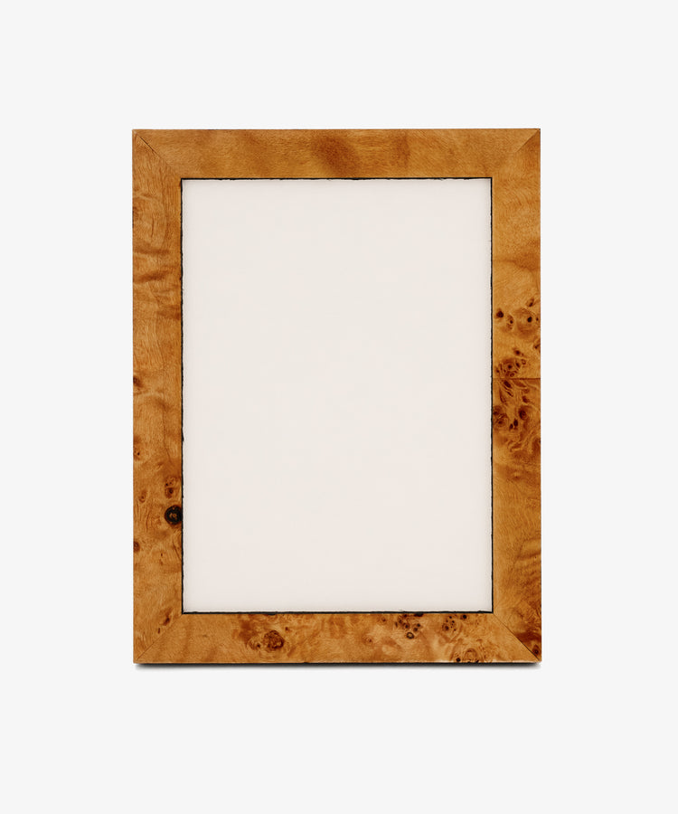 The Torino Frame, a rectangular wooden design with a light brown finish and subtle geometric marquetry details, features an empty white center and stands upright against a plain background.