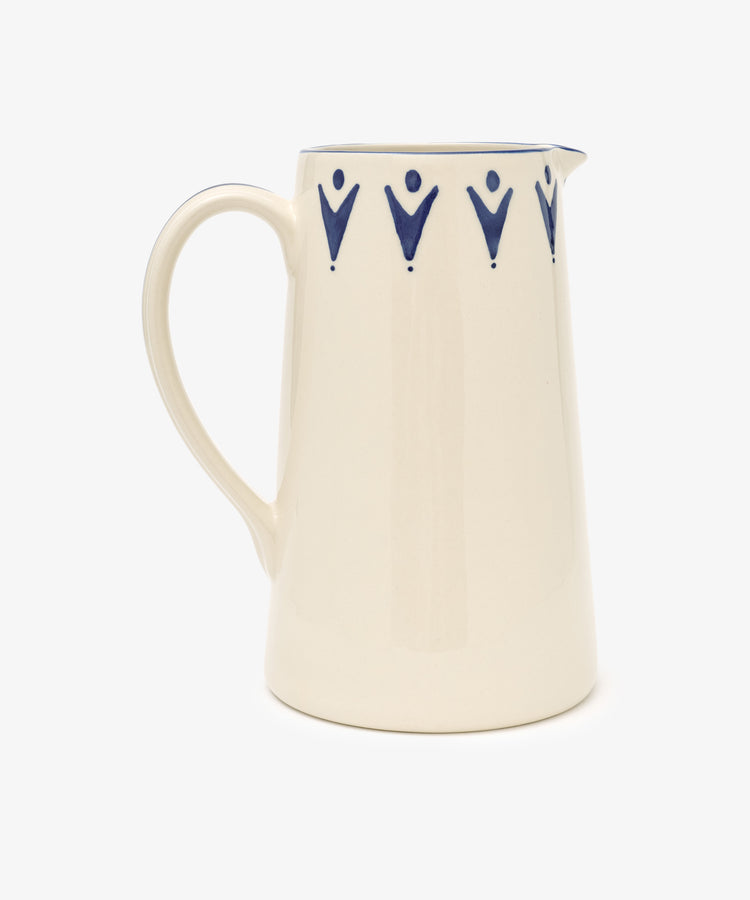 The Vito Jug is a cream ceramic jug with a handle, featuring blue V-shaped patterns near the rim—an ideal and distinctive gift for any occasion.