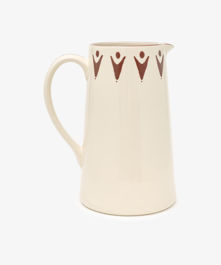 The Vito Jug is a handmade beige ceramic pitcher with a handle and a brown geometric rim, shown on a white background—ideal as a unique gift.