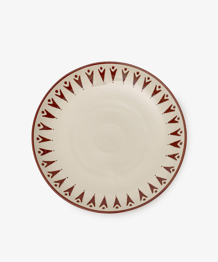 The Vito Serving Platter is a round ceramic piece with a cream center and a border of repeating red geometric patterns—perfect handmade serveware for any table setting.
