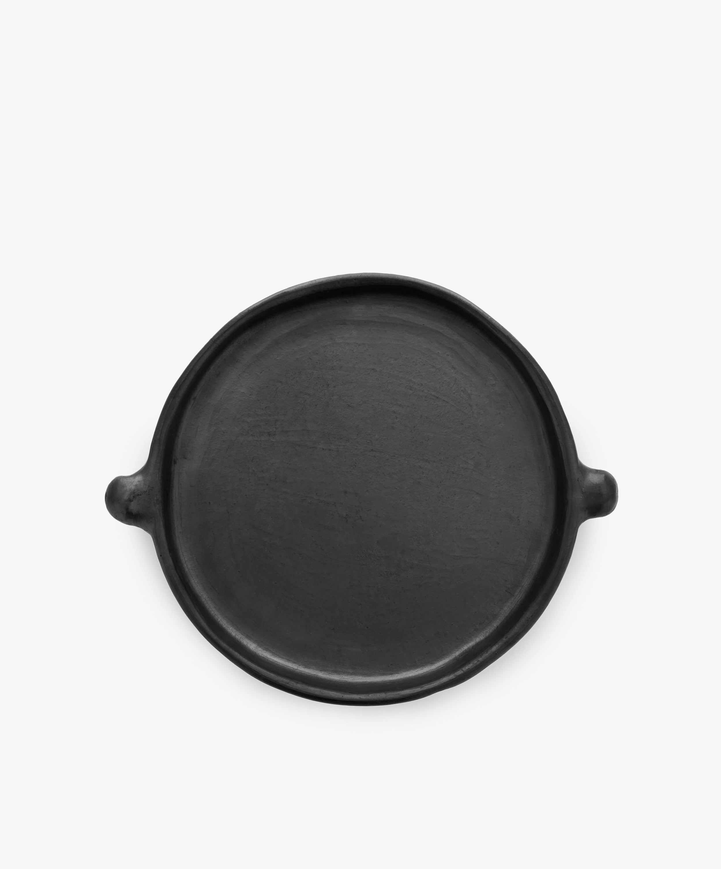 The Chamba Plate is a round, flat black clay plate with two small side handles, shown on a plain white background.