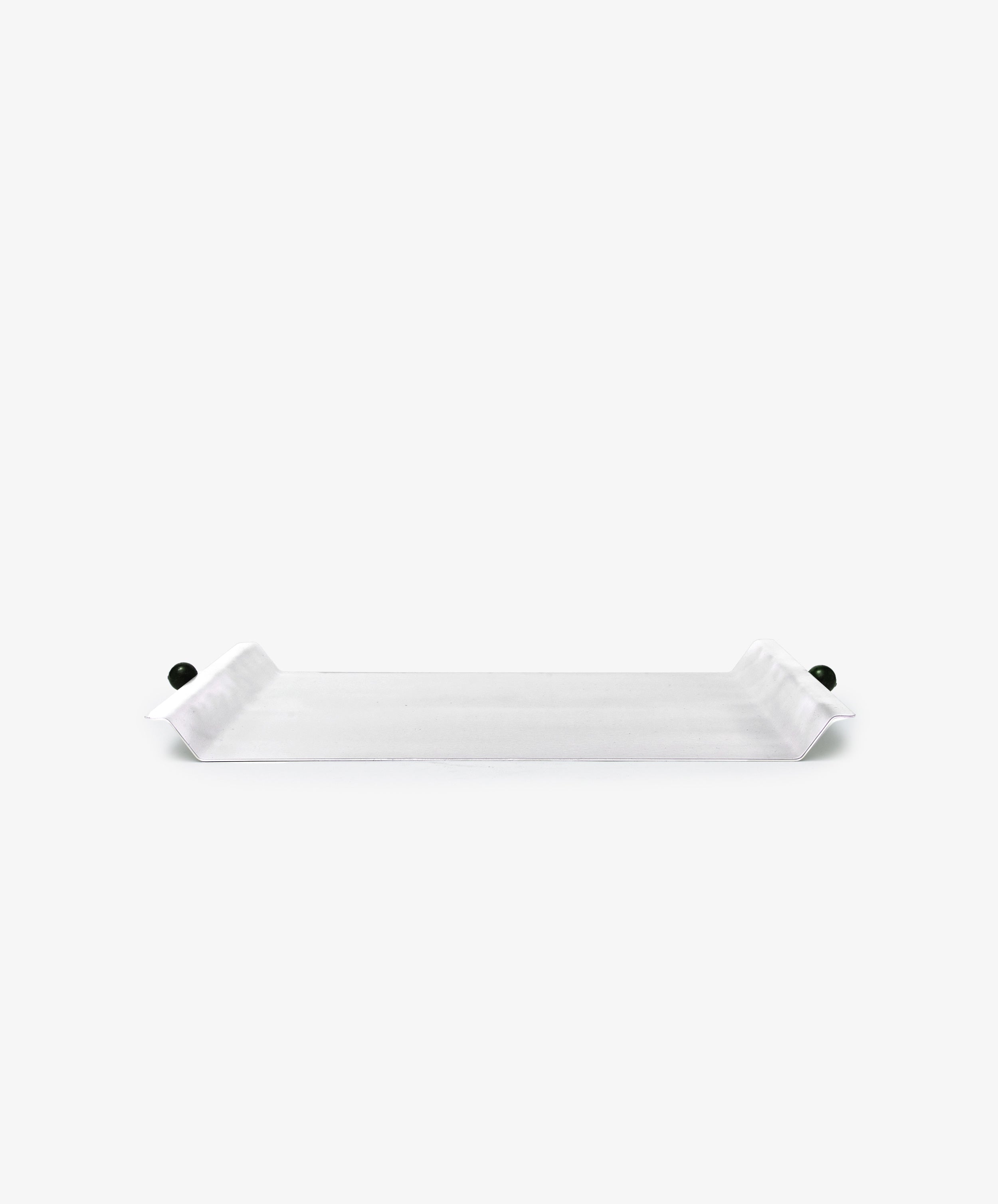 The Roberta Serving Tray is rectangular and white with upturned ends and small round dark side knobs, featuring a minimal design against a plain white background.