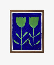 “Bright Blue Skies” is a framed painting featuring two green abstract flowers with stems and leaves set against a deep blue background, signed NM in the bottom right—Nancy McKie’s unique botanical work from the Art360 exhibition.
