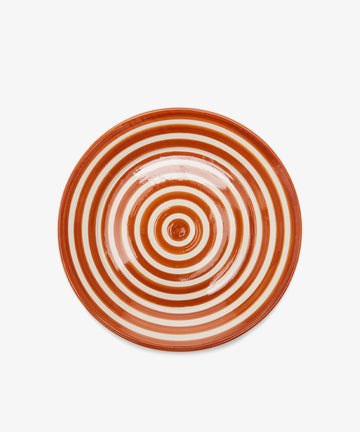 The Natalia Serving Bowl is a round ceramic piece featuring concentric orange and white rings, viewed from above against a plain white background.
