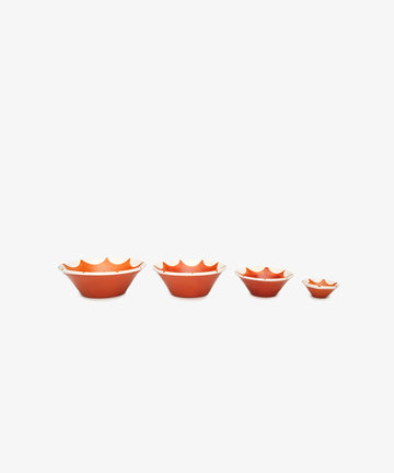 The Stella Nesting Bowls, a set of four orange handmade bowls with scalloped edges, are displayed in size order on a white background—ideal for serving aperitivo snacks or adding a unique touch to your table setting.