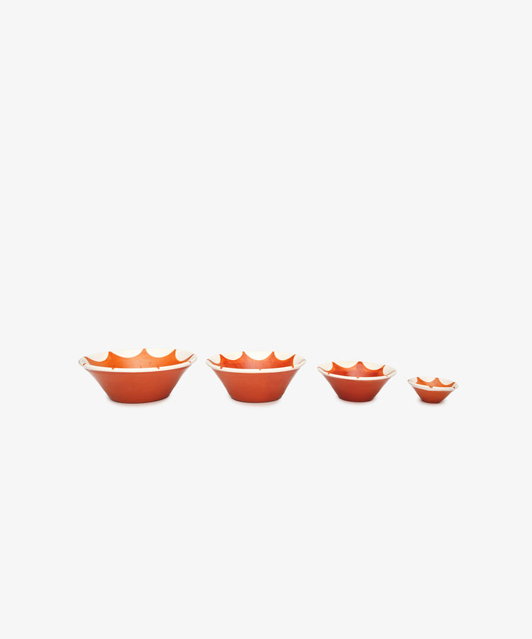 The Stella Nesting Bowls, a set of four orange handmade bowls with scalloped edges, are displayed in size order on a white background—ideal for serving aperitivo snacks or adding a unique touch to your table setting.