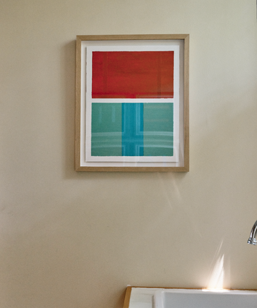 Framed Magnetic Color Field painting in red and aqua, hanging on tan wall.