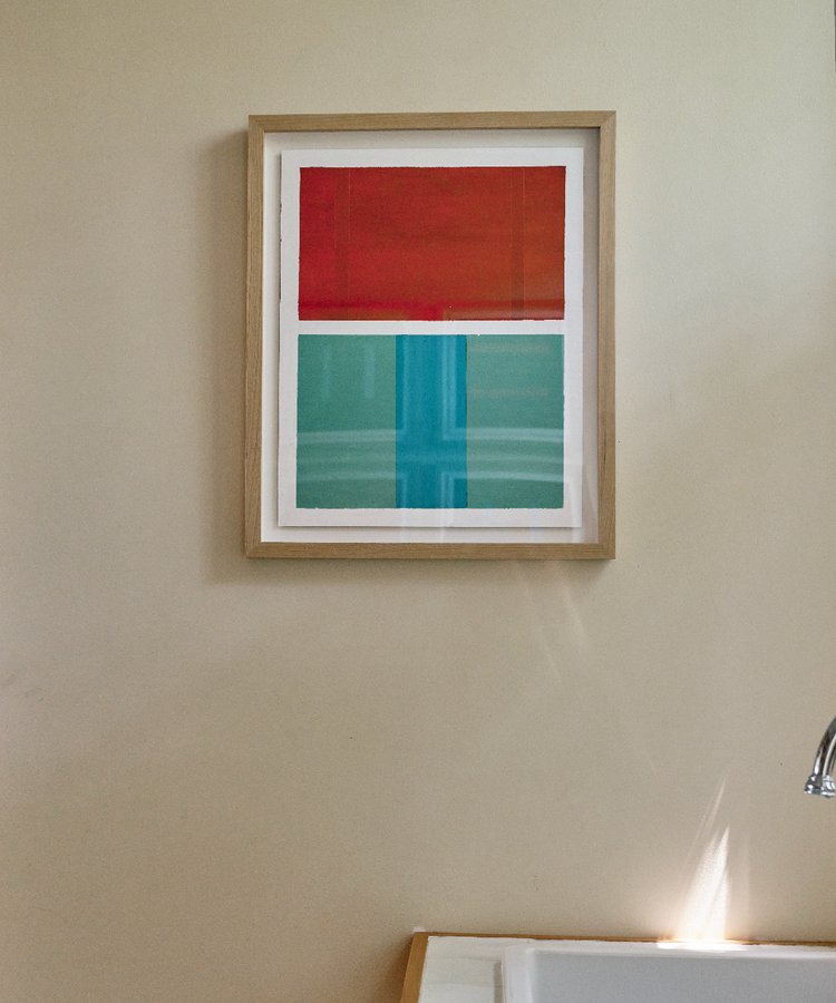 Framed Magnetic Color Field painting in red and aqua, hanging on tan wall.