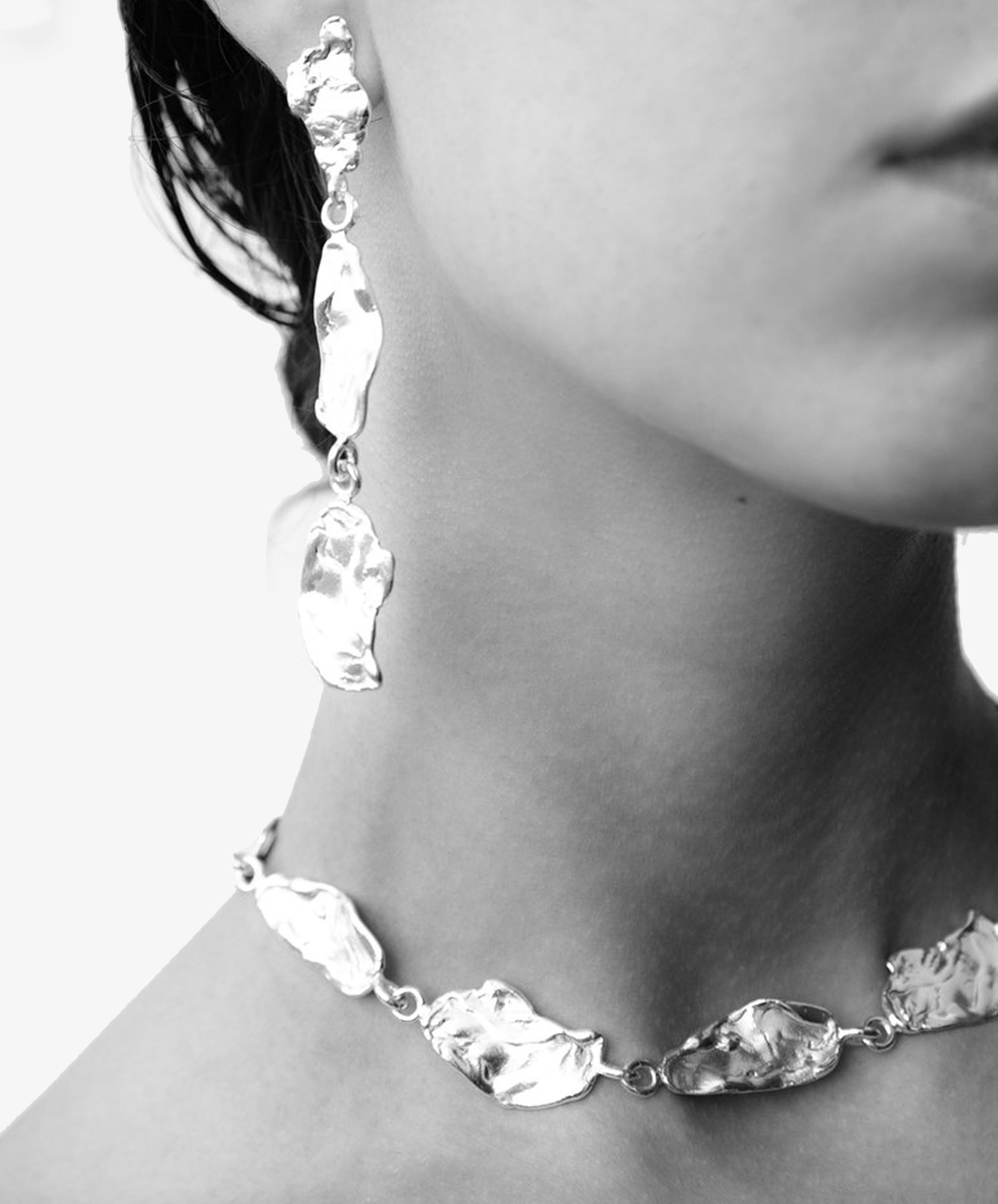 Closeup on model in black and white wearing Rosa Petal Earrings and Necklace.