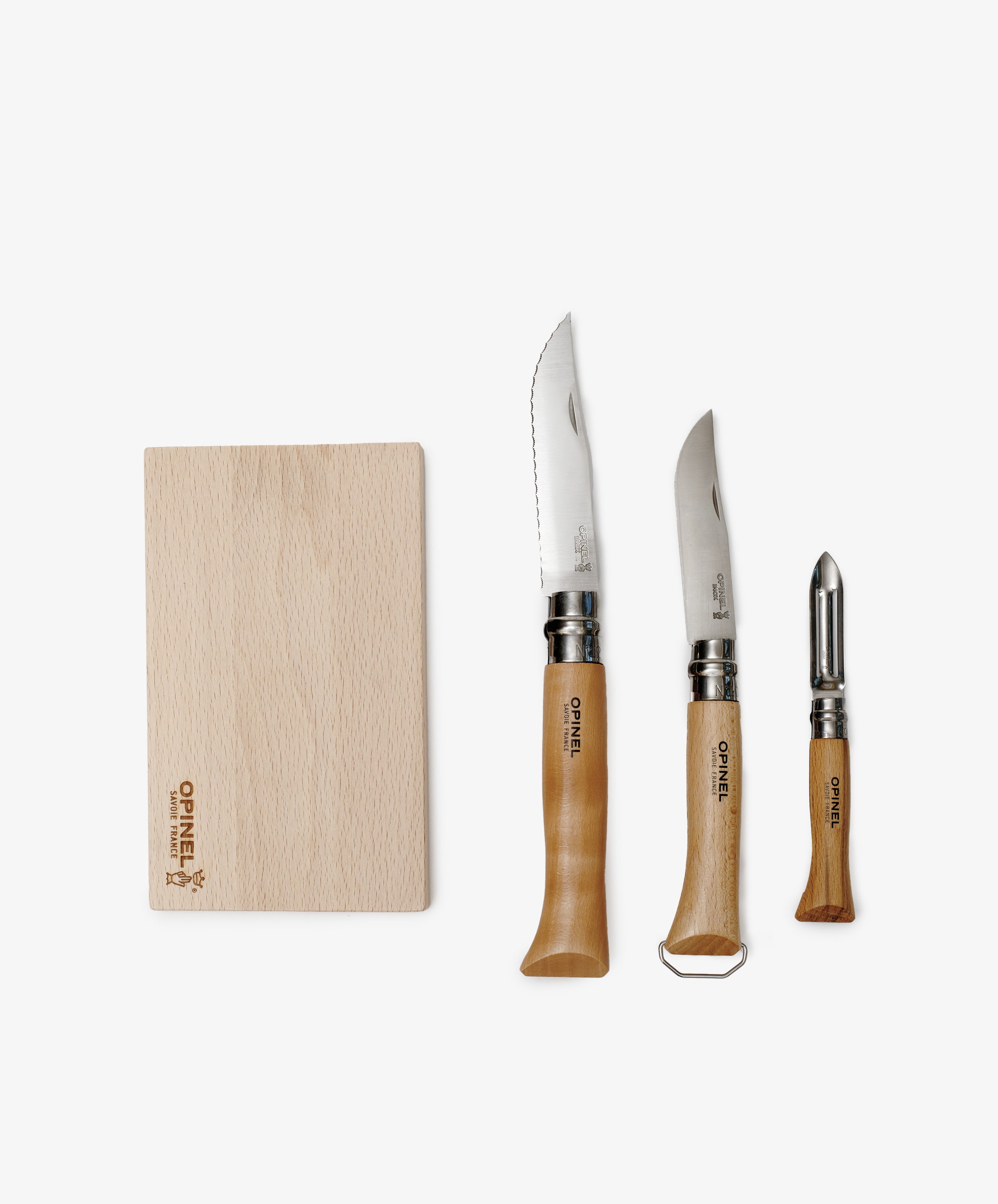 The Nomad Kit with Bottle Opener Knife includes a wooden cutting board, two wooden-handled kitchen knives, and a vegetable peeler—an ideal portable cutlery set for your travel kitchen kit.