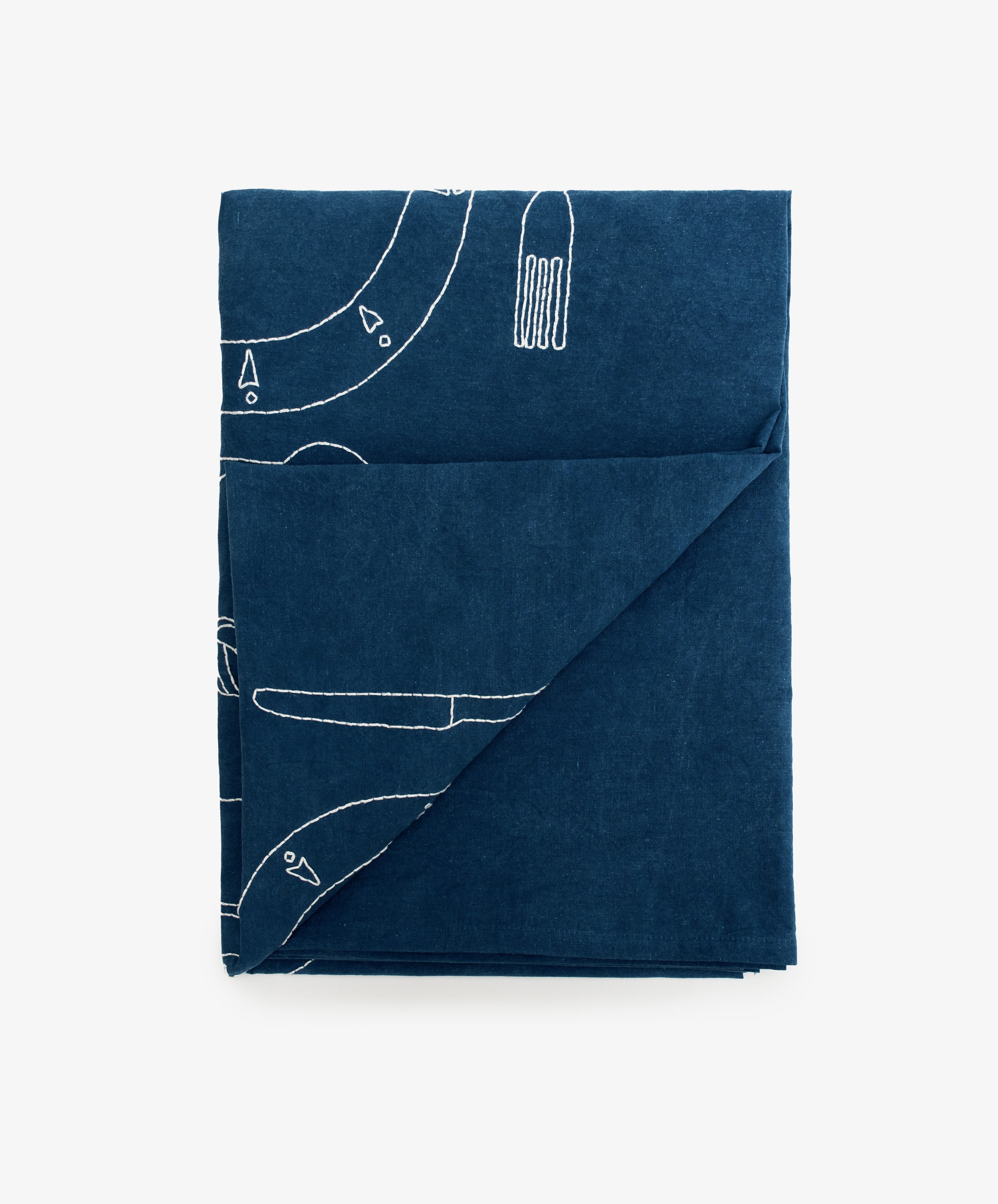 Dîner d'Eté custom tablecloth in indigo dyed linen, folded into rectangle with bottom corner pulled up.