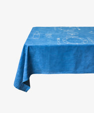 The Dejeuner d'Eta | Custom Tablecloth in blue linen, with white line art of plates, utensils, and a bottle, is draped over a rectangular table set against a white background.