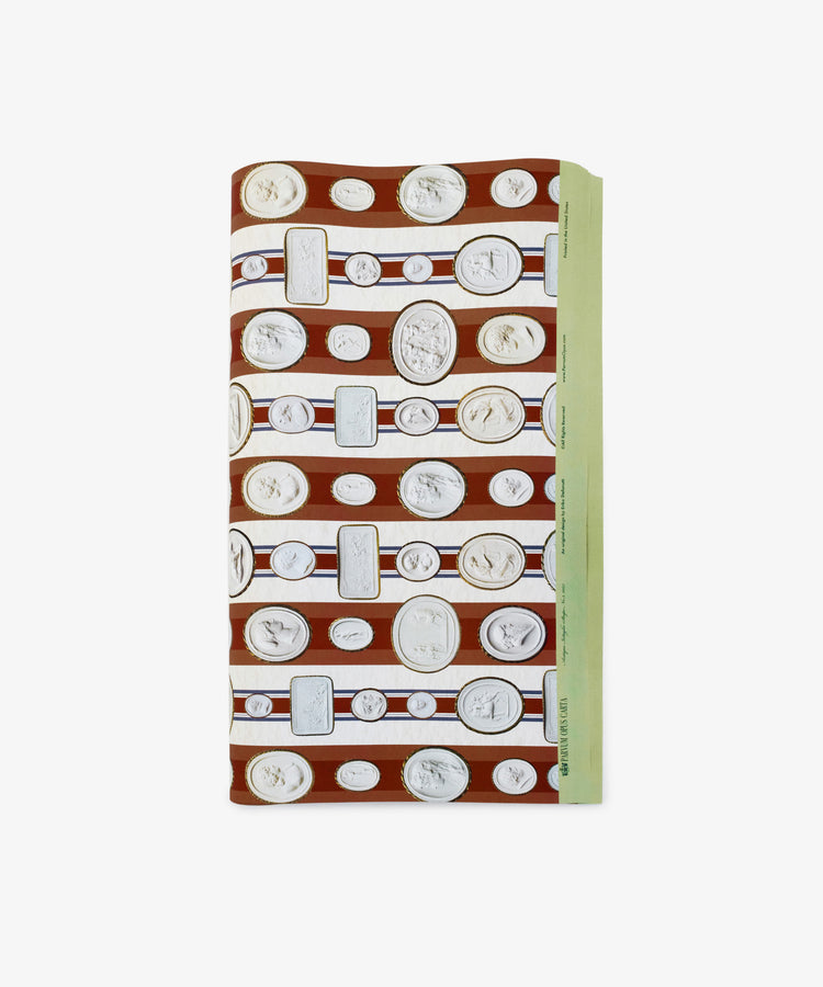 Intaglio Stripe Gift Wrap features folded paper with white coins and medallions on brown and white horizontal stripes, accented by a green border—perfect for neoclassical gift wrap enthusiasts inspired by Parvum Opus.