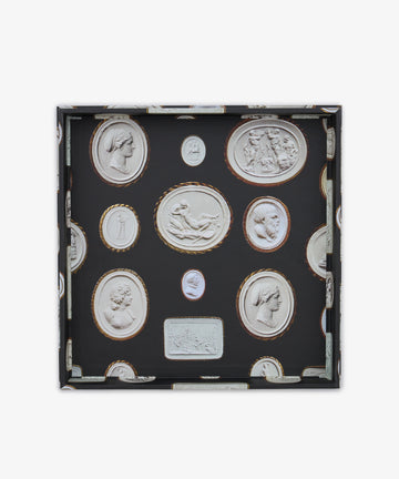 Introducing the Intaglio Nesting Tray: a shallow square organizer crafted from durable archival book boards, featuring a sophisticated black background adorned with oval and rectangular classical cameo motifs in white relief, and elegantly bordered with gold or brown accents. This stylish piece brings timeless elegance to your workspace.