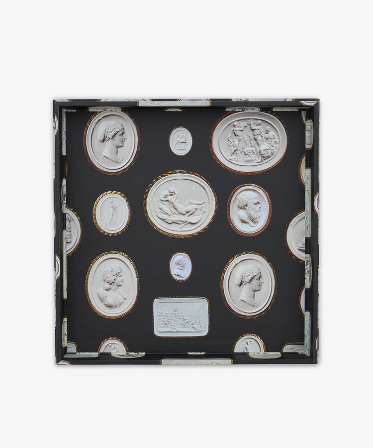 Introducing the Intaglio Nesting Tray: a shallow square organizer crafted from durable archival book boards, featuring a sophisticated black background adorned with oval and rectangular classical cameo motifs in white relief, and elegantly bordered with gold or brown accents. This stylish piece brings timeless elegance to your workspace.